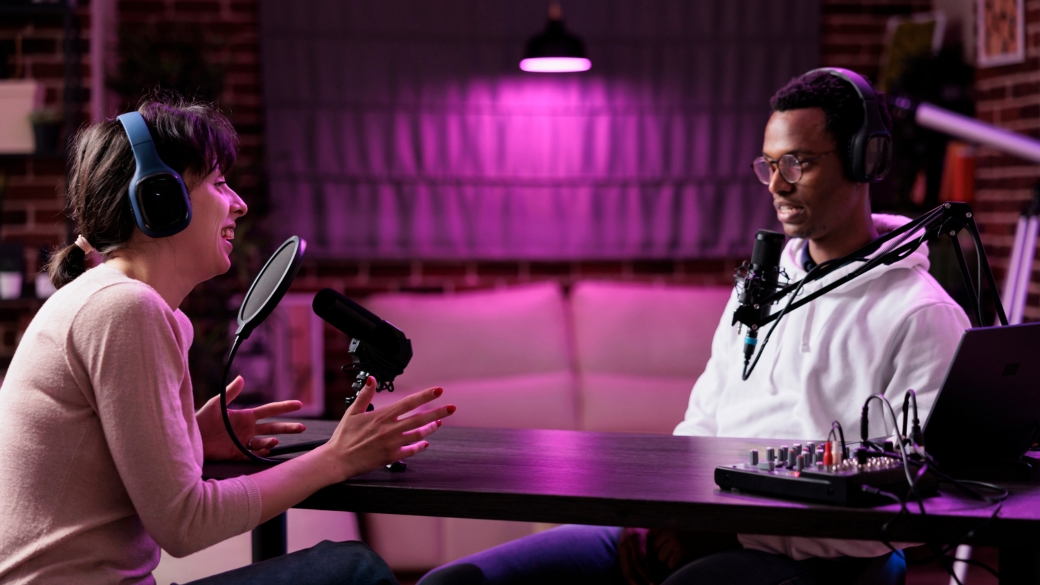 A professional creator speaking confidently into a studio microphone during a podcast recording.